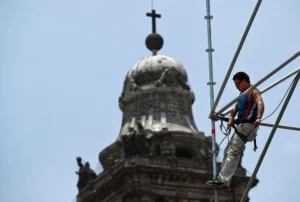 Construction worker on elevated scaffolding performing maintenance work with safety harness in place