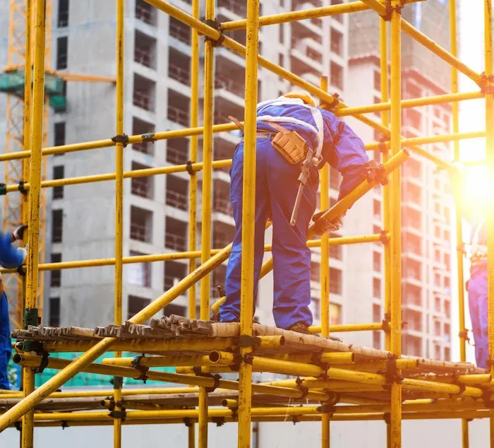 Construction workers using scaffolding system on building site for structural work and access