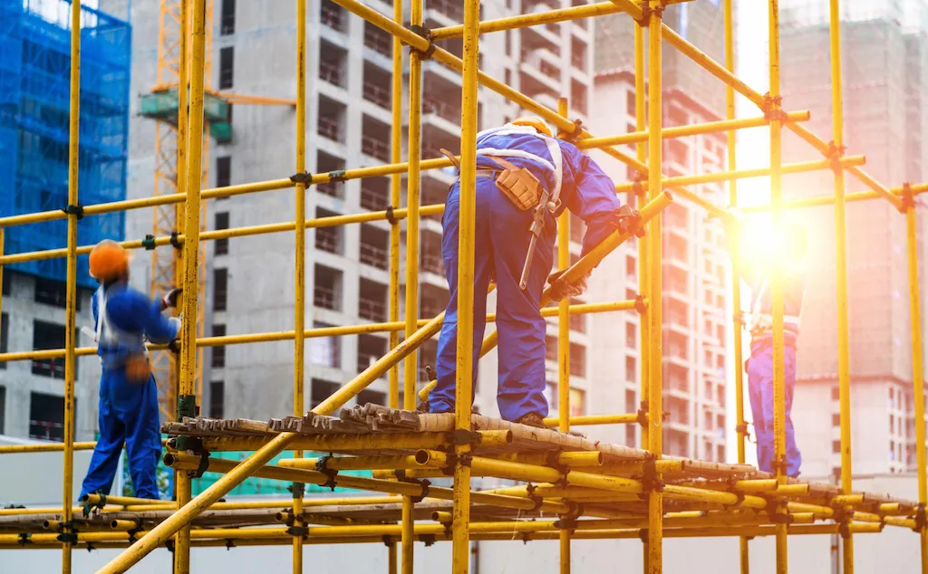 Construction workers using scaffolding system on building site for structural work and access