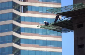 Construction workers on high-rise scaffolding platform performing exterior work at height safely
