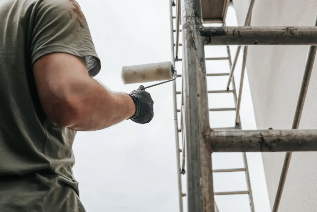 Worker painting exterior wall using scaffolding system for stable and efficient elevated access
