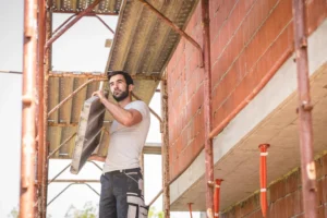 Worker carrying scaffolding platform during installation on residential construction site in Berkeley