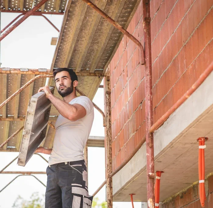 Worker carrying scaffolding platform during installation on residential construction site in Berkeley